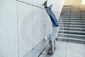 Skateboarder doing a handstand on skateboard against wall