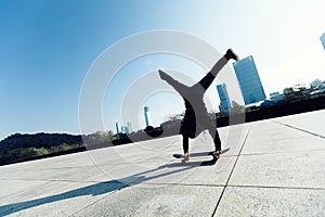 Skateboarder doing a handstand on skateboard in city