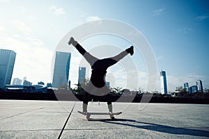 skateboarder doing a handstand on skateboard in city