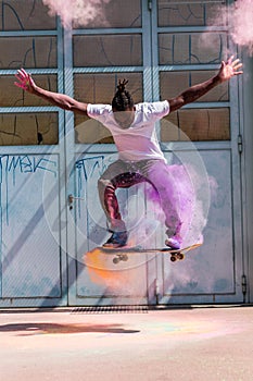 Skateboarder doing kickflip with colorful holi powder photo