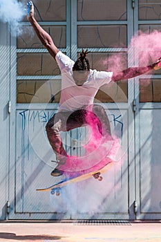 Skateboarder doing kickflip with colorful holi powder photo