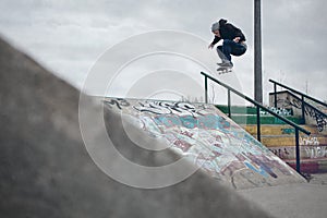 Skateboarder doing a Ollie over the rail in a skatepark