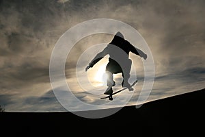 Skateboarder doing ollie in sunset photo