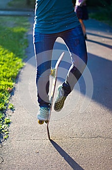 Skateboarder girl`s legs in sneakers doing a trick on skateboard outdoors.