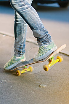 Skateboarder girl`s legs in sneakers doing a trick on skateboard outdoors.