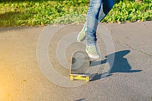 Skateboarder girl`s legs in sneakers doing a trick on skateboard outdoors.