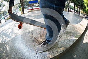 Skateboarder legs riding skateboard at city skatepark