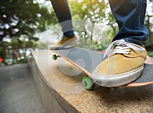 Skateboarder legs riding skateboard at city skatepark