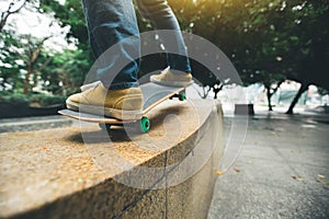 Skateboarder legs riding skateboard at city skatepark