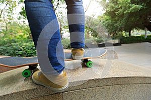 Skateboarder legs riding skateboard at city skatepark