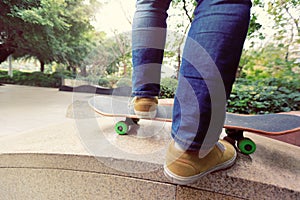 skateboarder legs riding skateboard at city skatepark