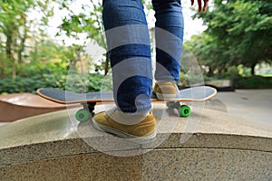 skateboarder legs riding skateboard at city skatepark