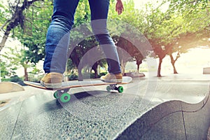 Skateboarder legs riding skateboard at city skatepark