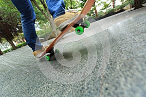 Skateboarder legs riding skateboard at city skatepark