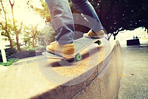 Skateboarder legs riding skateboard at city skatepark