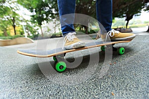 Skateboarder legs riding skateboard at city skatepark