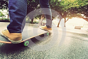 Skateboarder legs riding skateboard at city skatepark