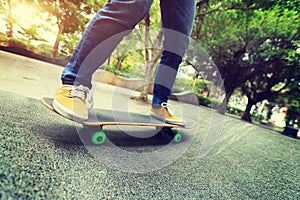 Skateboarder legs riding skateboard at city skatepark