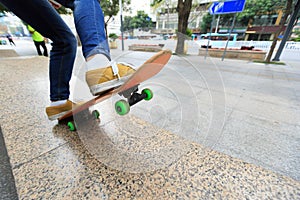 Skateboarder legs riding skateboard at city skatepark