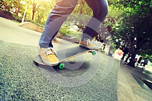 Skateboarder legs riding skateboard at city skatepark