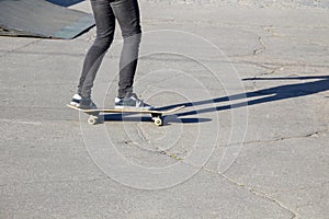 Skateboarder legs riding skateboard at skatepark