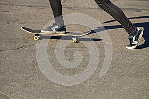 Skateboarder legs riding skateboard at skatepark