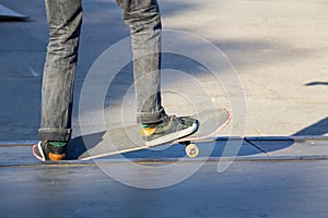 Skateboarder legs riding skateboard at skatepark