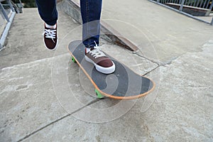 Skateboarder legs riding skateboard at skatepark