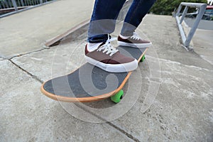 Skateboarder legs riding skateboard at skatepark