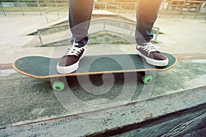 Skateboarder legs riding skateboard at skatepark