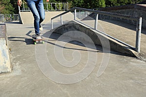 Skateboarder legs riding skateboard at skatepark