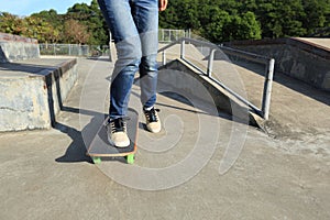 Skateboarder legs riding skateboard at skatepark