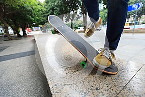 Skateboarder legs riding skateboard at skatepark ramp