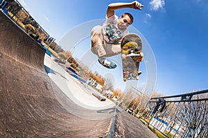 Skateboarder make trick boneless, high jump in mini ramp in skatepark