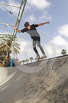 Skateboarder performing tricks in a park, with street background and blue sky