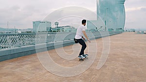 Skateboarder rides a skateboard in the modern city terrace.