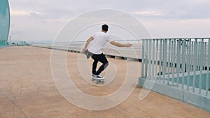 Skateboarder rides a skateboard in the modern city terrace.