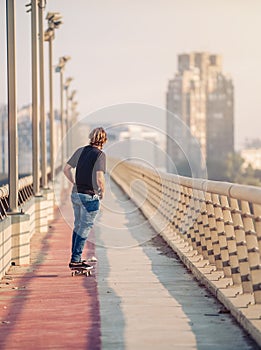 Skateboarder skates over a city bridge. Free ride street skateboarding