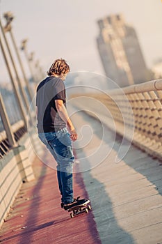 Skateboarder skates over a city bridge. Free ride street skateboarding