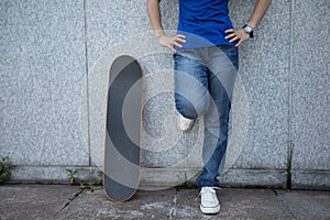 skateboarder stand leaning on marble wall at city