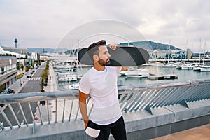 Skateboarder stands with skateboard in the modern city terrace