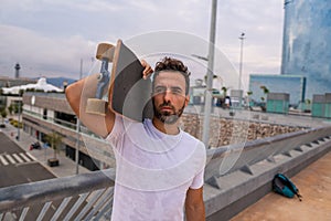 Skateboarder stands with skateboard in the modern city terrace