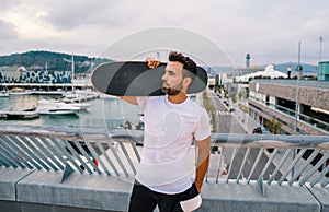 Skateboarder stands with skateboard in the modern city terrace