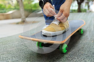 Skateboarder tying shoelace at city skatepark