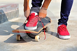 Skateboarder tying shoelace at skate park