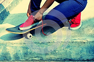 Skateboarder tying shoelace at skate park