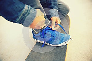 Skateboarder tying shoelace at skate park