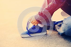 Skateboarder tying shoelace at skate park