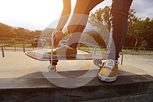 Skateboarder tying shoelaces at skate park