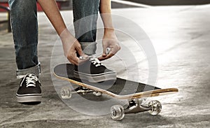 Skateboarder tying shoes at skate park